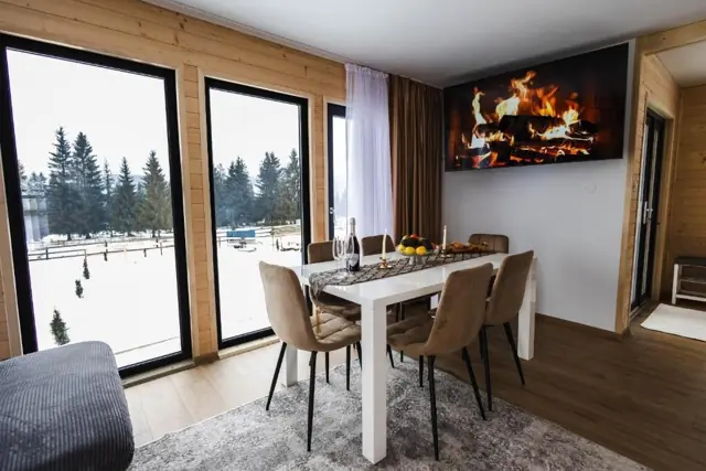 Masă pentru 6 persoane lângă ferestre mari cu vedere spre brazi